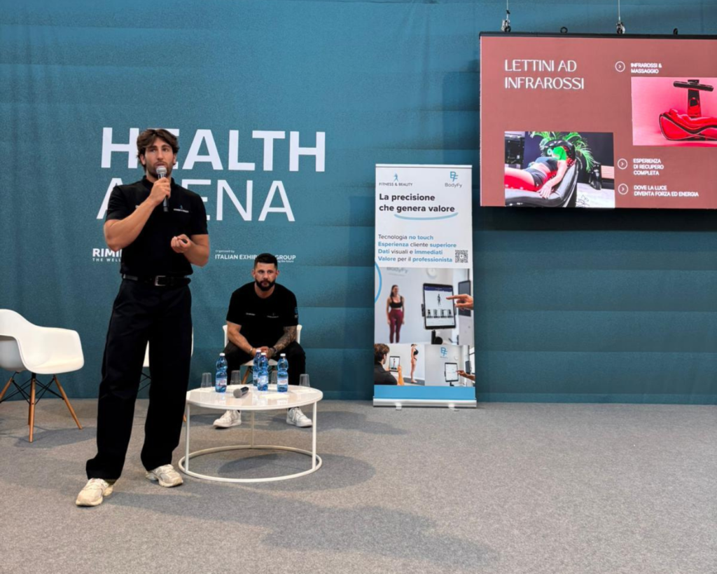 Due uomini presenti a un evento sulla salute, con uno striscione Fitness & beauty a RiminiWellness 2026.